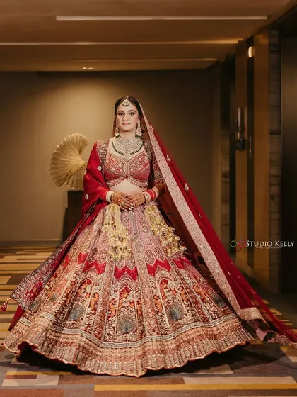 A stunning full-length portrait of the bride in her intricately detailed red and gold lehenga.