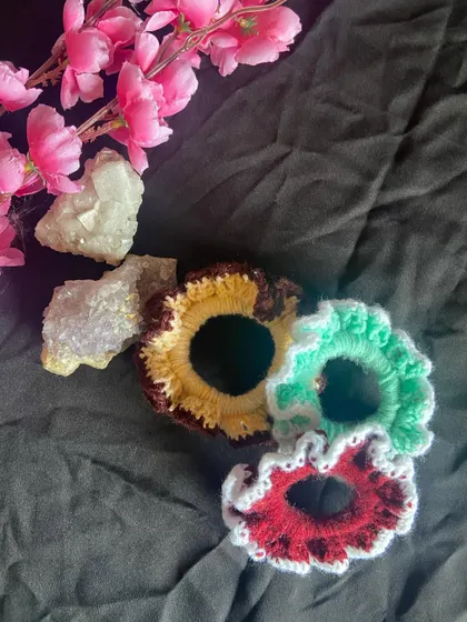 This angle highlights the texture and shape of my handmade scrunchies. They are a fun and affordable piece of custom crochet work to add to your accessory collection.