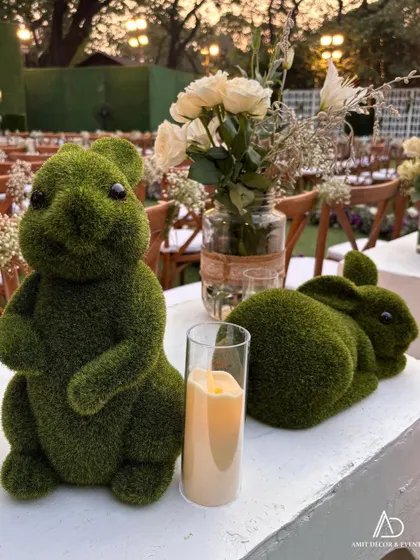 A close-up of the adorable moss bunny centerpieces, paired with white roses and candles, showcasing my love for unique and delightful details.