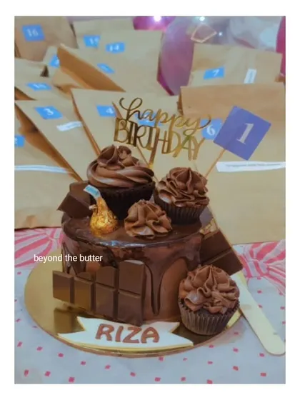 A fun birthday surprise cake, surrounded by gift bags and topped with chocolate cupcakes and Hershey's Kisses.
