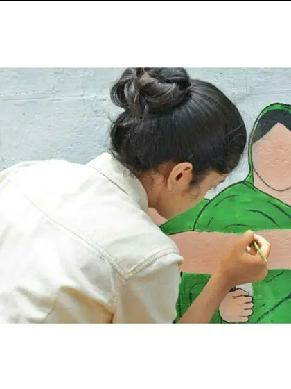 Getting into the details. This close-up shot shows me carefully painting the features of a figure in a community mural, showcasing the focus required to bring characters to life.