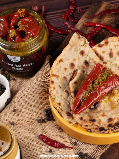 A rustic, warm setting was chosen for this red chilli pickle to evoke a feeling of homemade tradition. The paratha and raw spices help the customer imagine enjoying it with their meal.