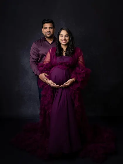 A classic, full-length couple's maternity portrait. Both parents-to-be are looking at the camera, creating a timeless photo that is perfect for framing.