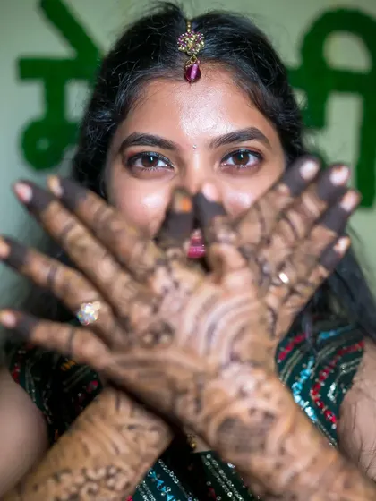 A mysterious and beautiful shot of the bride peeking through her henna-covered hands.