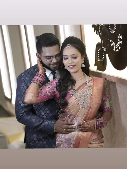 A classic pose of the couple, showing the bride's full look with her pink and peach saree.