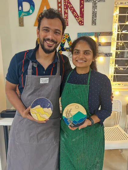 A couple with their unique wooden disc paintings. Painting on wood gives a lovely rustic feel to the artwork.