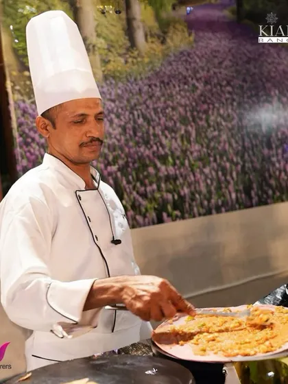 The Chef’s Culinary Symphony. A chef at a live station, carefully preparing a dish, showcasing the skill and focus that goes into every plate we serve.