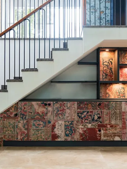 A creative use of the space under the stairs. This custom unit features a unique patchwork design on the cabinet doors and backlit shelves for displaying art and artifacts.