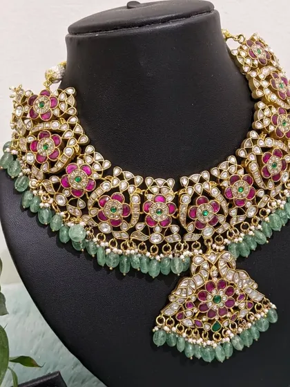 This beautiful Jadau neckpiece with pink and green stones and natural strawberry beads is perfect for a traditional lehenga. It can be styled for both grand bridal looks and elegant semi-bridal occasions.