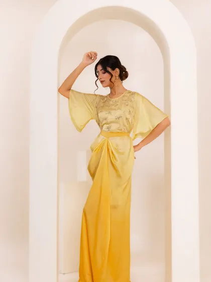 Another look from the A.Projekt campaign, this time a draped yellow midi dress. The styling against the arched, minimalist set was designed to highlight the garment's modern silhouette and delicate embroidery.
