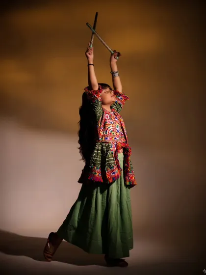 A joyful and energetic pose from her traditional photoshoot. With dandiya sticks raised high, this image is full of movement and celebration, perfectly capturing the spirit of Navratri.