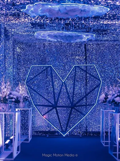 We love creating immersive entrances. For this celestial-themed Sangeet, we built a 'Tunnel of Love' with thousands of glittering blue sequins, a geometric heart, and floating clouds to transport guests into another world.