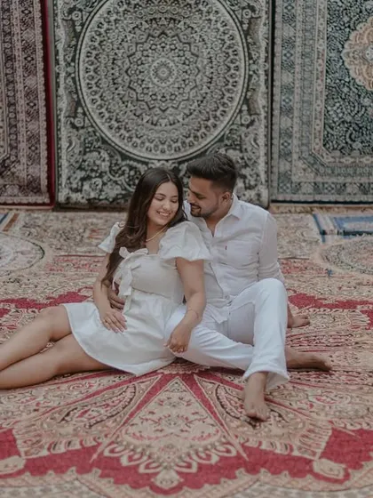 A relaxed and happy shot of the couple sitting together on a beautiful Persian rug.