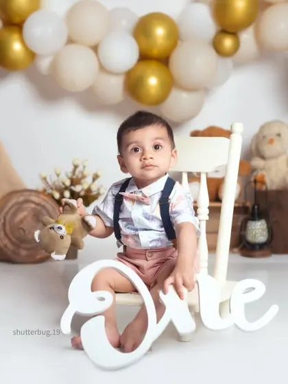 A classic first birthday portrait, with the baby holding a "One" sign in our stylish boho camp setup.