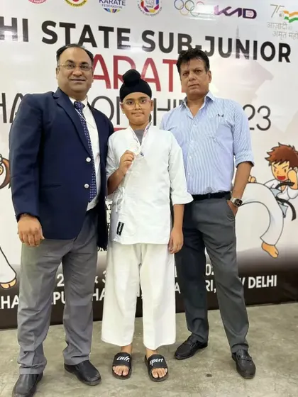 Standing with a young champion and Hanshi Bharat Sharma. The guidance of senior masters is crucial in shaping the next generation of karateka.