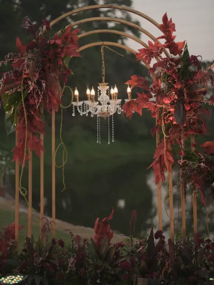 The floral arch and chandelier framed against the evening sky and water, showcasing a perfect blend of natural beauty and elegant design.