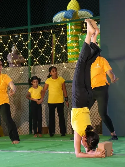 A student performs a supported headstand on stage, showcasing the skills and confidence she has built in class.