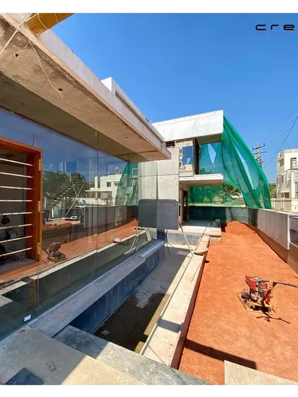 The Quarry House nearing completion, with its large glass panels installed, beginning to reflect the surrounding environment.