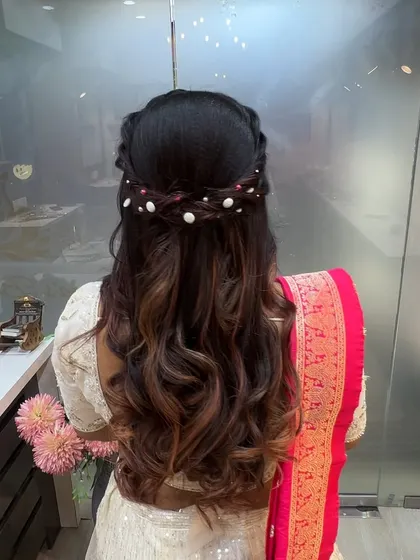 A beautiful example of a half-up hairstyle with a braided crown and pearl accents. This is a classic and versatile look that students master for engagement parties and receptions.