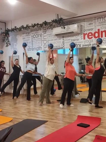 A lively Barre class in session, with members using balls to add resistance and challenge their balance and coordination.