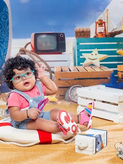A curious baby exploring the props in our beach-themed set. The details, from the tiny sandals to the retro TV, add a lot of character to this fun and imaginative toddler photo.