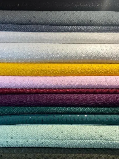 A stack of pure Chikankari fabrics, showcasing the range of colors I offer for bespoke kurtas. This traditional hand-embroidered textile from Lucknow is a popular choice for its elegance and breathability.