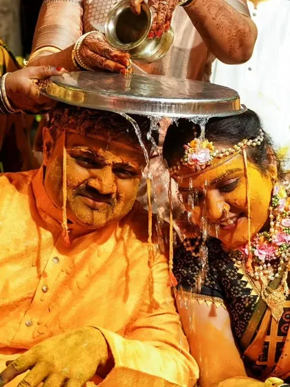 A traditional Haldi ritual where water is poured over the couple, symbolizing purification and blessings before their union.