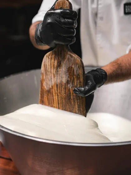 A close-up of the mozzarella being worked. The glossy sheen on the cheese is a sign of its freshness and high moisture content, which translates to a perfect, creamy melt on your pizza.