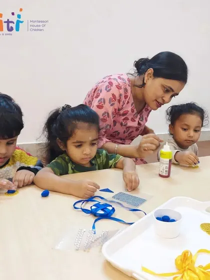 A teacher provides guidance as children work on their Rakhi crafts. This support helps them execute their creative ideas and build confidence.