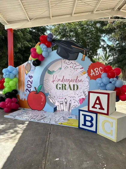 The complete kindergarten graduation setup, showing the combination of the backdrop, props, and balloon garlands.