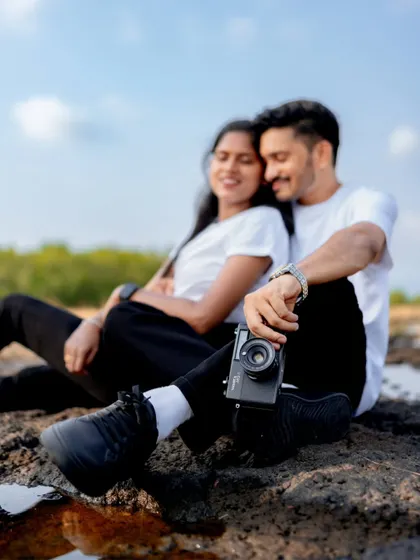 A creative shot focusing on the vintage camera held by the couple, with them blurred softly in the background. This highlights their shared interests and love for photography.