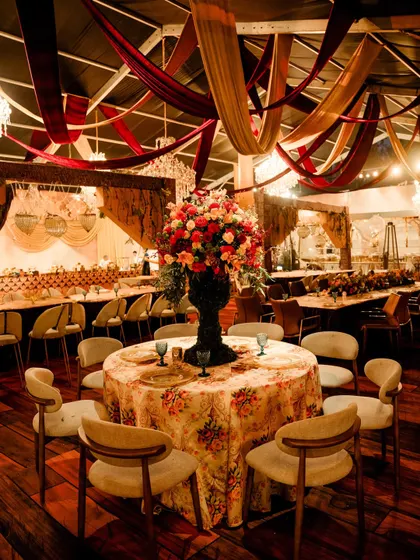 A dining table setup with a large floral centerpiece, surrounded by modern chairs. The mix of rustic, floral, and modern elements creates a unique and eclectic style.
