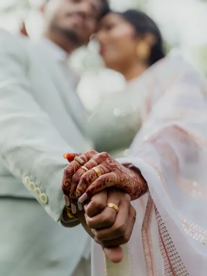 A close-up shot focusing on the couple's hands, showcasing their rings and the bride's henna. This detail-oriented portrait symbolizes their new union.