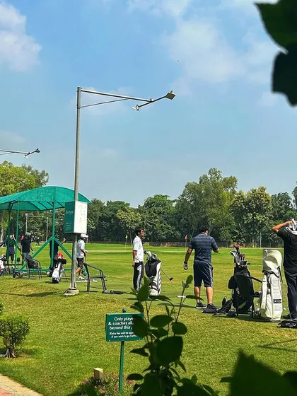 A beautiful Sunday on the greens. This view shows golfers enjoying the spacious layout of our driving range, framed by lush trees.