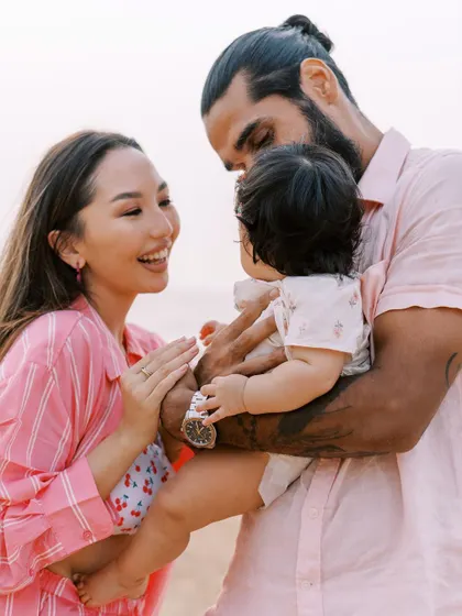 A couple playing with their baby on the beach. The joy and love are palpable in this candid moment.
