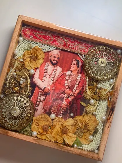 A close-up of a varmala preservation frame featuring a beautiful wedding photo. The intricate details of the garland, including the golden ornaments, are perfectly captured in glossy resin.