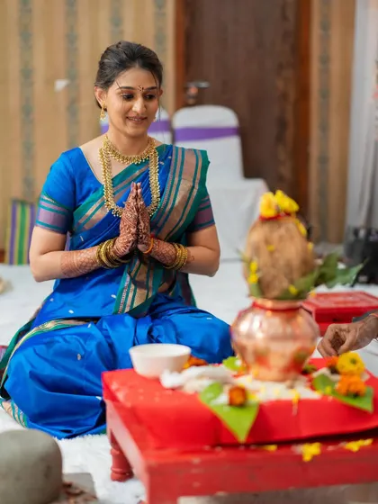 The bride participating in her engagement puja, looking serene and elegant with a simple updo and natural makeup.
