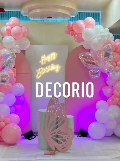 A beautiful butterfly-themed 6th birthday party in shades of pink and white. The decor features iridescent butterfly accents, a 'Happy Birthday' neon sign, and a '6' marquee number.