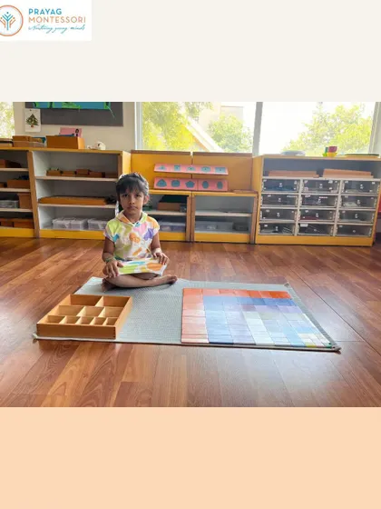 This student is engaged with the Decanomial Square, a material that visually and physically demonstrates multiplication concepts.