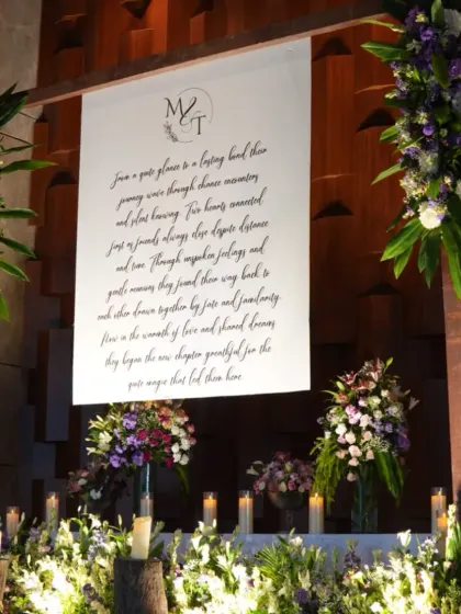 A personalized photo booth featuring a canvas with the couple's story, surrounded by candles and floral arrangements.