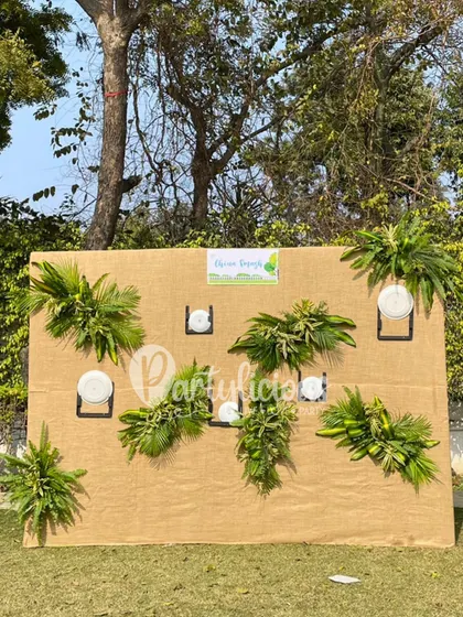 This unique backdrop was designed for a child's birthday party using a simple jute panel. I adorned it with fresh greenery and plate holders to create a rustic and charming 'Green Depot' for the little guests.