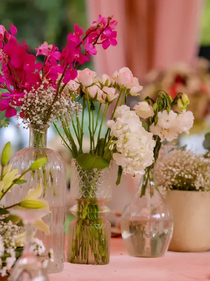 A close-up of the delicate floral arrangements in various glass vases, featuring a mix of pink and white blossoms that add softness and beauty to the tablescape.