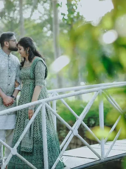 A romantic portrait on a bridge, with the groom kissing his bride's forehead.