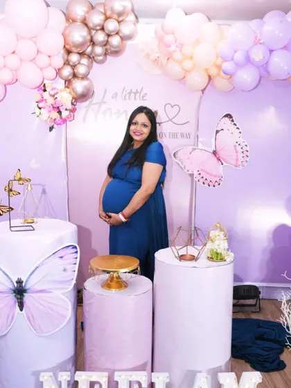 The happy mom-to-be posing with her butterfly-themed baby shower decor. These modern setups are great for creating fun and memorable pictures.