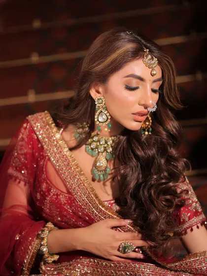 This image captures the bride's serene expression and the beautiful details of her maang tikka and nose ring, essential elements of the traditional bridal look.