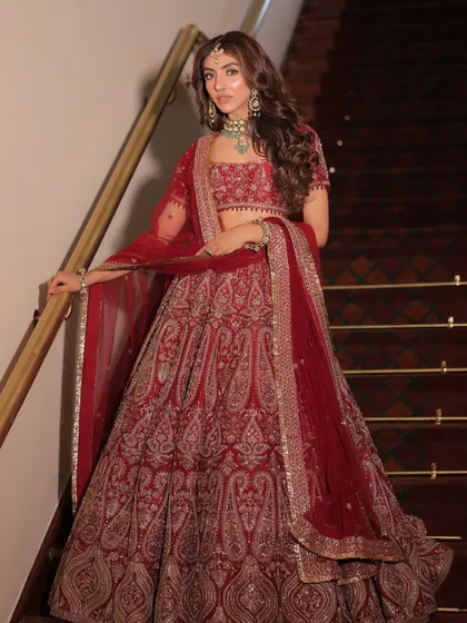 A full-length shot of a bride in a deep red lehenga by Kajal Rajput. I styled this to feel both traditional and modern, with a focus on the paisley motifs and the flowing silhouette.