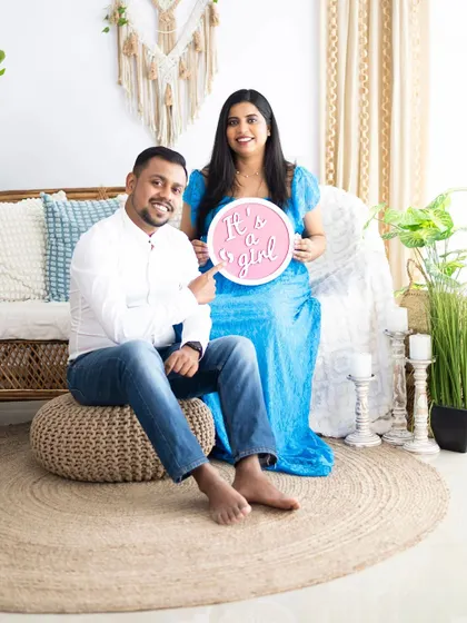 A happy gender reveal in our boho studio setup. The couple proudly holds an "It's a girl" sign, sharing their excitement with big smiles.