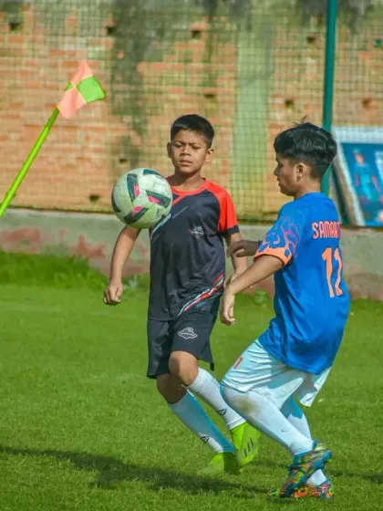A player uses their body to shield the ball from a defender near the corner flag.