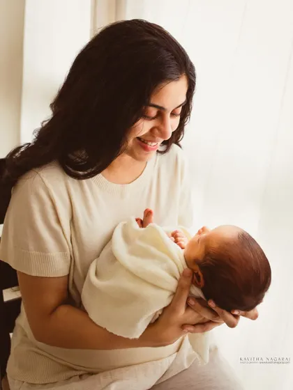 A new year, a new beginning. A mother smiles at her newborn, a beautiful and hopeful portrait captured in the soft light of a window.