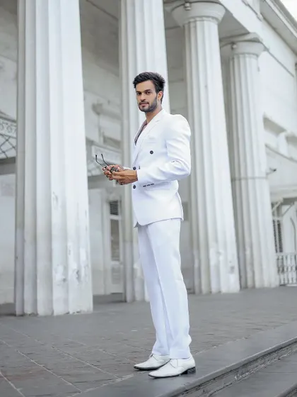 A side profile of the model in the white suit, holding his sunglasses.